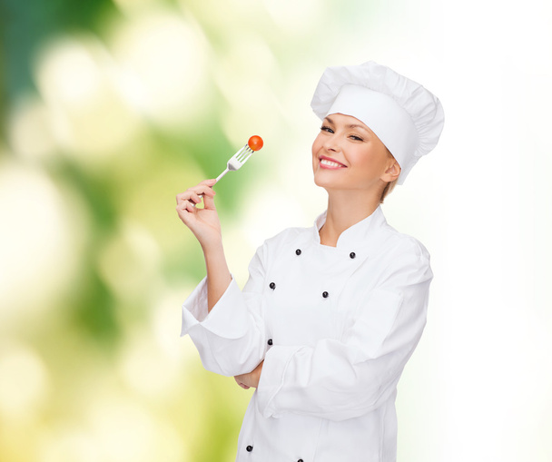 smiling female chef with fork and tomato - Fotografie, Obrázek