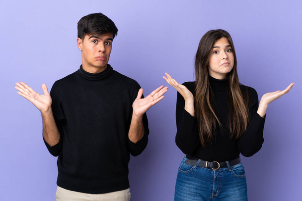 Young couple over isolated purple background having doubts and with confuse face expression - Photo, Image