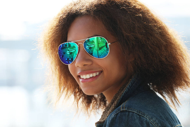 pretty woman wearing sunglasses with perfect teeth and dark clean skin having rest outdoors, smiling after received good positive news. Beautiful young dark-skinned female enjoy nature. - Foto, immagini