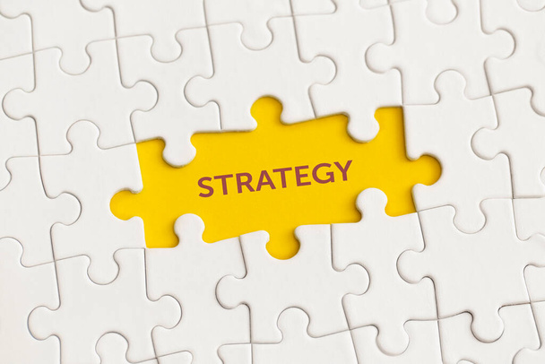 White details of puzzle with the text "Strategy" on yellow background. - 写真・画像