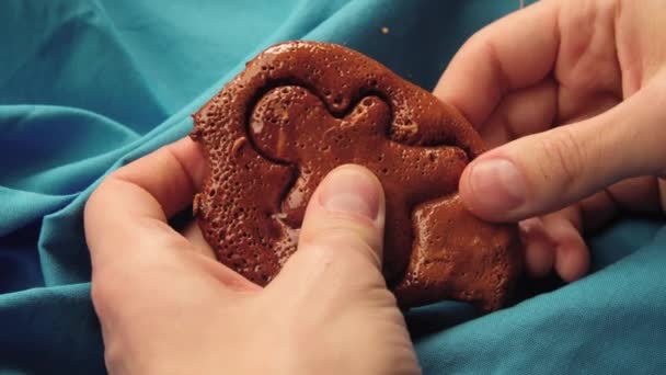 Le mani degli uomini rompono i biscotti di zucchero caramelle a forma di uomo. - Filmati, video