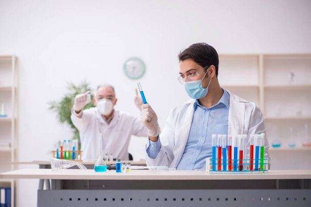 Dos químicos masculinos trabajando en el laboratorio durante una pandemia - Foto, Imagen
