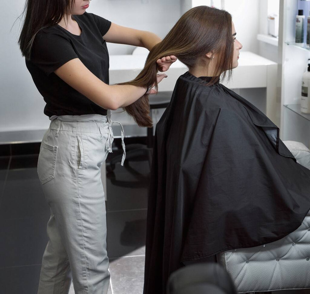 クライアントの髪を結う美容師さんブルネットがスタイリングをして美容室で気をつけて - 写真・画像