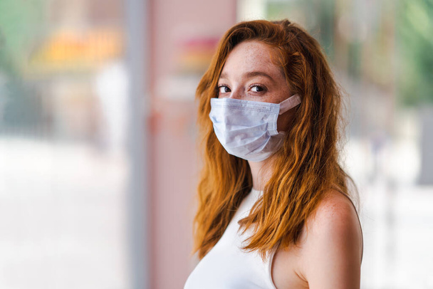 Young red haired woman with a surgery mask, protection and precaution for contagious disease. Corona virus outbreaking. - Fotó, kép