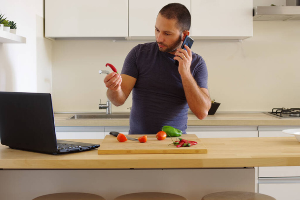 A white man talking on the phone in front of a board with vegetables in the kitchen - Fotó, kép