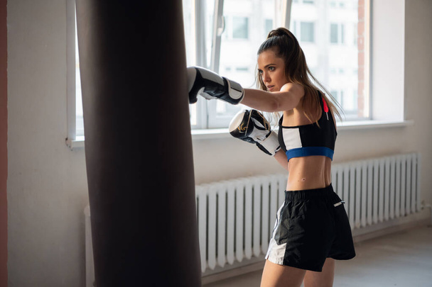 Beautiful woman boxing combat bag with sport trainer together. Girl boxer exercising box punch with personal coach. - Foto, immagini