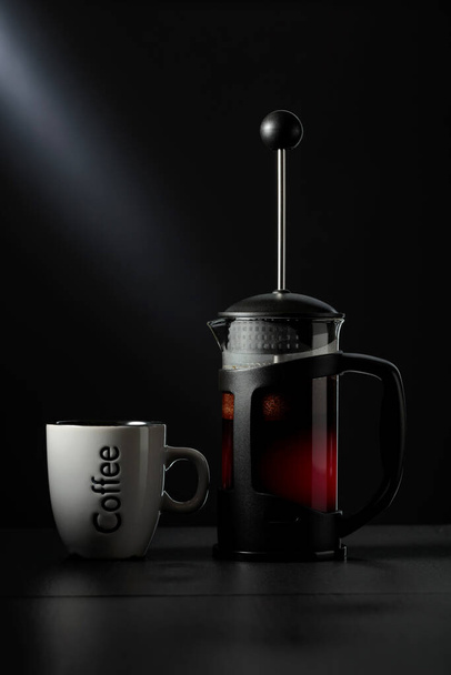 Francouzský lis káva a šálek na černém stole. - Fotografie, Obrázek