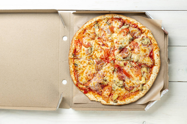 Pizza in a cardboard box against a white background. Space for text. View from above. Pizza delivery. Pizza menu. - Foto, Bild