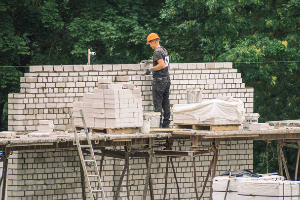 Vilnius, Lituania - 20 de agosto de 2021: Nuevos edificios o casas en construcción con trabajadores con casco en el trabajo - Foto, imagen