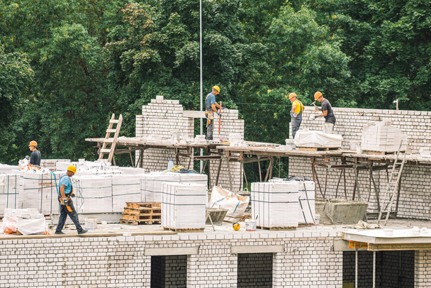 Vilnius, Litauen - 20. August 2021: Neubauten oder im Bau befindliche Häuser mit Arbeitern mit Helm bei der Arbeit - Foto, Bild