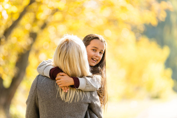 小さな女の子と彼女の母親は秋の公園で晴れた天気を楽しむ - 写真・画像