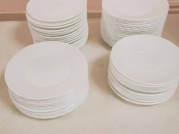 Platos blancos limpios y vacíos en una pila sobre la mesa, servicio en la cafetería del hotel. - Foto, Imagen