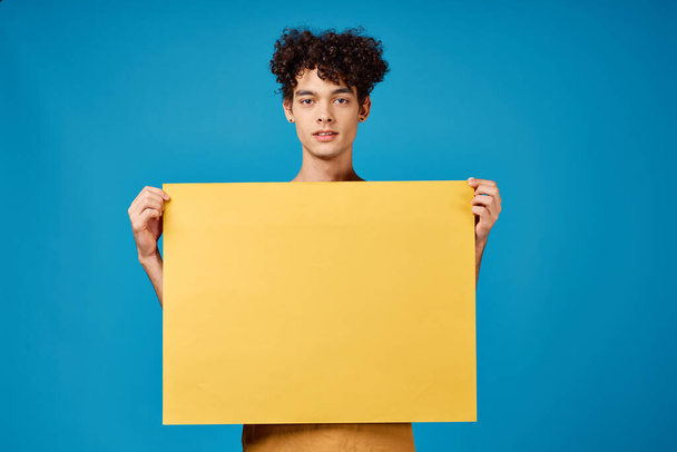 lockige Kerl mit gelben Attrappe Poster blauen Hintergrund - Foto, Bild