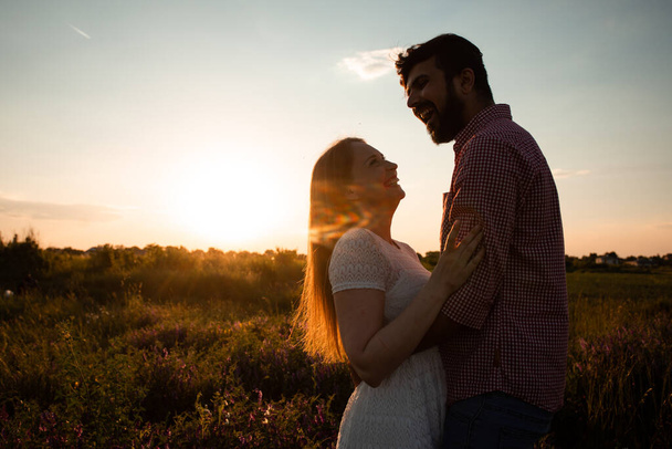 Embracing couple in rays of setting sun - Φωτογραφία, εικόνα