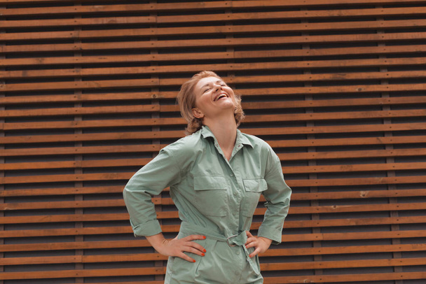 Attractive girl smiling, standing on wooden wall background - Φωτογραφία, εικόνα