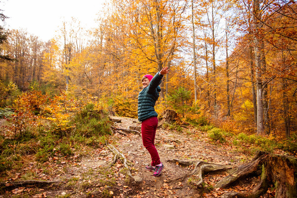 Happy woman hiker is walking in the beautiful autumn forest - Fotó, kép