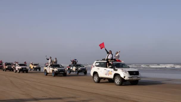Essaouira, Marrakech, Marocco - 2 ottobre 2021: Rallye Aicha des Gazelles 2021. Arrivo delle auto alla spiaggia di Essaouira alla fine del rallye 2021 per la cerimonia di presentazione. Bandiera marocchina. - Filmati, video
