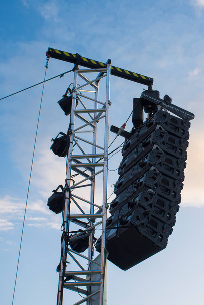 Sistema de altavoces Line array colgando del poste durante el funcionamiento de la luz natural. Atardecer cielo azul fondo - Foto, imagen