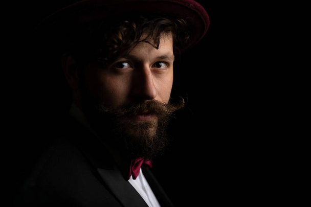 primer plano en un atractivo hombre de negocios con barba y pelo largo y rizado lleva un sombrero de color burdeos  - Foto, imagen