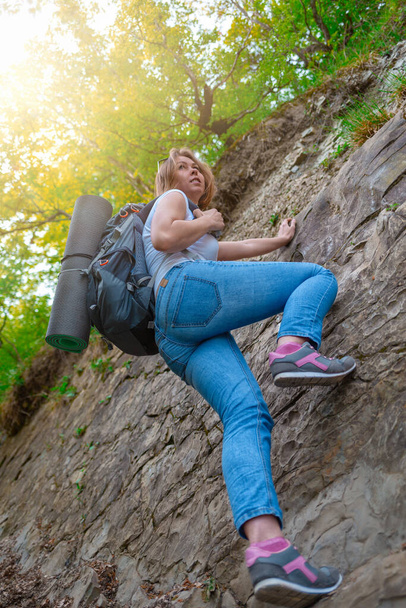 Una joven se dedica a escalar rocas. Ocio y deportes activos. Luz. Vista inferior. - Foto, Imagen