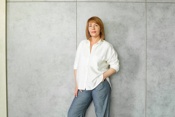 Happy successful mature business woman standing on gray background portrait - Foto, Bild