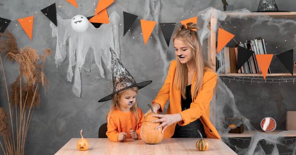Anya és lánya tökös töklámpást csinálnak Halloweenre. Hagyományos őszi boszorkányünnep a családban. Október 31. Ünnepi koncepció. banner - Fotó, kép