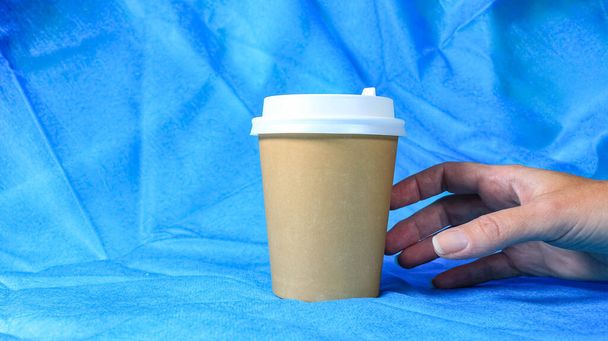 Une main de femme qui prend une tasse de café jetable avec un couvercle. Café à emporter. Coup de feu sélectif. - Photo, image