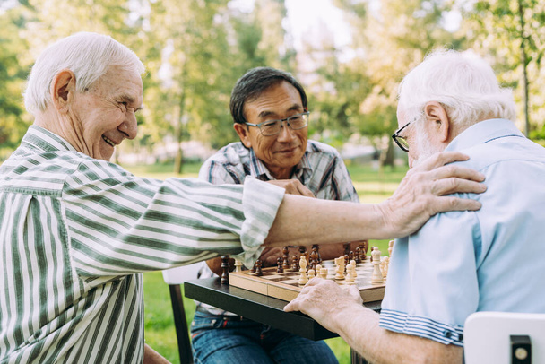 Group of senior friends playing chess game at the park. Lifestyle concepts about seniority and third age - 写真・画像