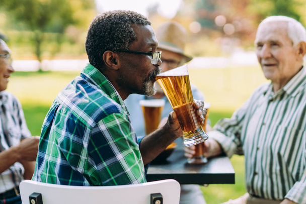 group of senior friends drinking a beer at the park. Lifestyle concepts about seniority and third age - Фото, изображение