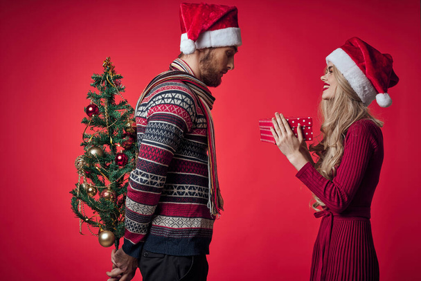 emotioneel man en vrouw geschenken kerst nieuwjaar rood achtergrond - Foto, afbeelding