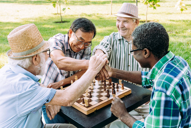 Group of senior friends playing chess game at the park. Lifestyle concepts about seniority and third age - Фото, изображение
