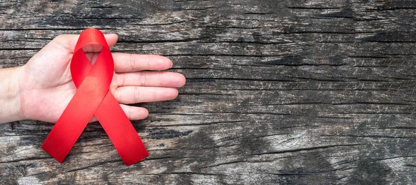 Journée mondiale de l'aide et mois national de sensibilisation au VIH / sida et au vieillissement avec un ruban rouge pour aider la main (isolé avec un chemin de coupure sur fond blanc)  - Photo, image