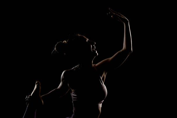 Fit menina praticando ioga em um estúdio. Modelo de fitness iluminado lateral de meia silhueta - Foto, Imagem