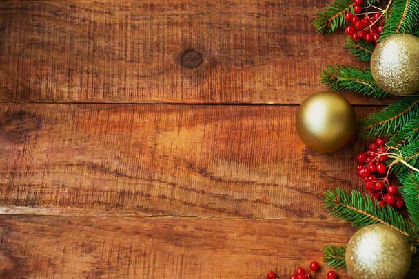 Sfondo natalizio. Rami di abete rosso, bacche rosse di potassio e palle lucenti di anno nuovo su uno sfondo di legno. Vista dall'alto. Biglietto di Natale o Capodanno. Posto per testo, spazio di copia, disposizione piatta - Foto, immagini