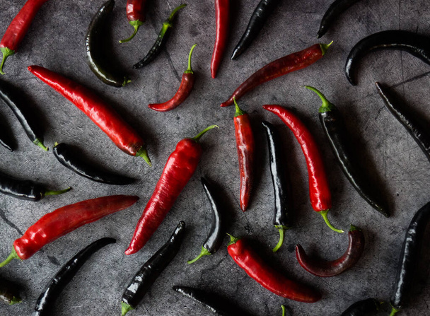 chilli lusky z červené a černé pepře na tmavém betonovém pozadí - Fotografie, Obrázek