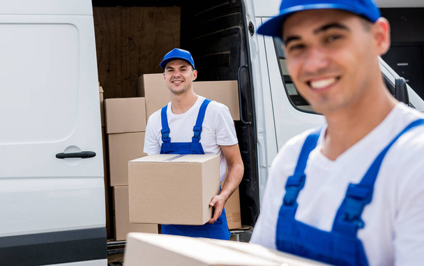 Two removal company workers unloading boxes from minibus into new home - Zdjęcie, obraz