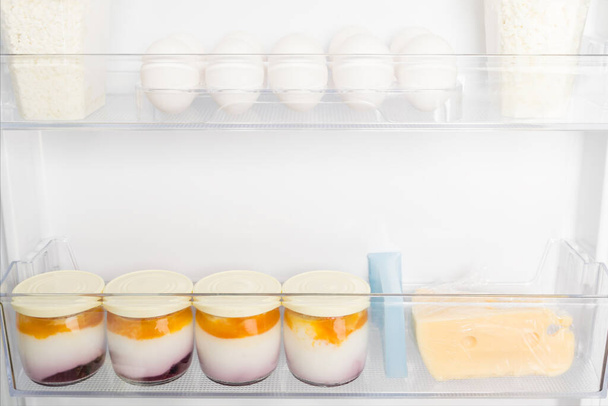 eggs and yoghurts are on the shelves in the refrigerator door, close-up view - 写真・画像