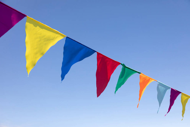 Πολύχρωμες τριγωνικές σημαίες που κρέμονται στον ουρανό σε μια υπαίθρια. Εξωτερικά. Γιορτή πάρτι. Γιορτινή διάθεση - Φωτογραφία, εικόνα