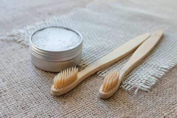 Two natural bamboo toothbrushes and kaolin dentifrice or organic tooth powder made with natural ingredients on rustic background with copy space, selective focus - Photo, Image