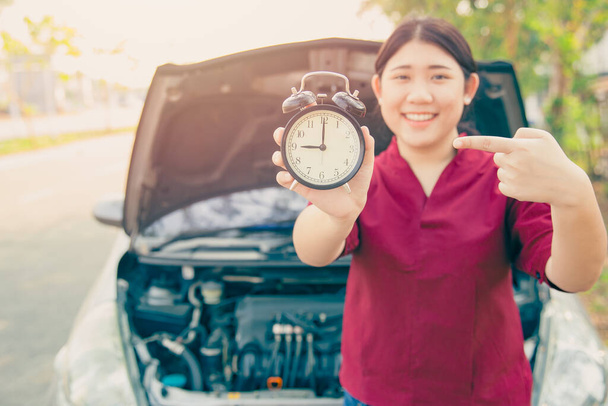 Bringen Sie Auto in Dienst nach Zeitplan Konzept, Frau glücklich lächeln mit Wecker und Auto offene Motorhaube Hintergrund. - Foto, Bild