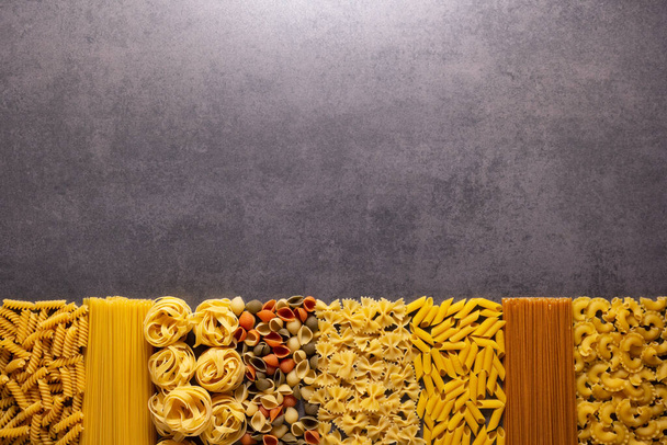 Raw pasta assortment at stone tabletop. Pasta collection food on table background - Φωτογραφία, εικόνα