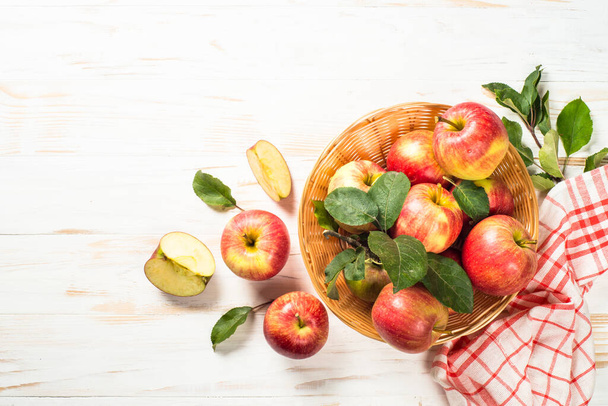 Fresh ripe red apples in the basket at white table. - Φωτογραφία, εικόνα