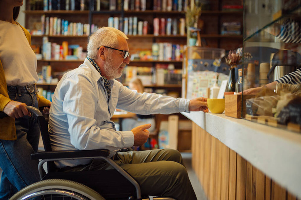 Niepełnosprawny starszy mężczyzna i młoda opiekunka - Zdjęcie, obraz