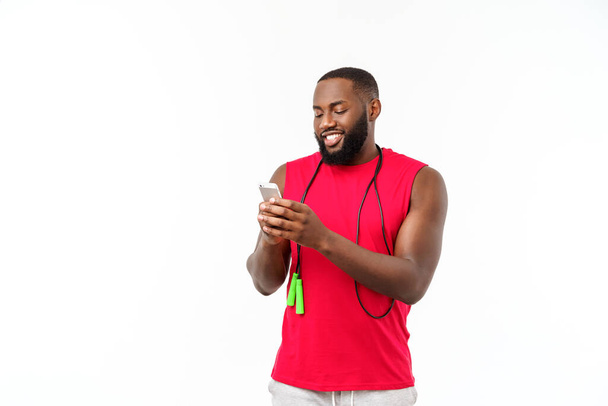 Mature fit homme afro-américain texter sur mobile et tenant la corde élastique
. - Photo, image