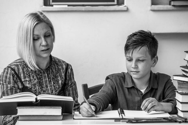 Estudiante pequeño durante la tarea con la ayuda de un tutor. Foto en blanco y negro. - Foto, Imagen