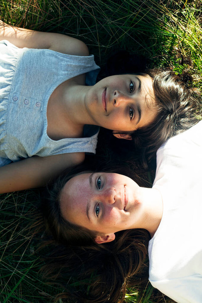 Portrait de deux sœurs fille couchée sur l'herbe verte dans le parc d'été. - Photo, image