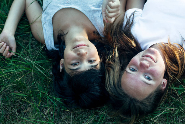 夏の公園の緑の芝生の上に二人の友人の女の子. - 写真・画像