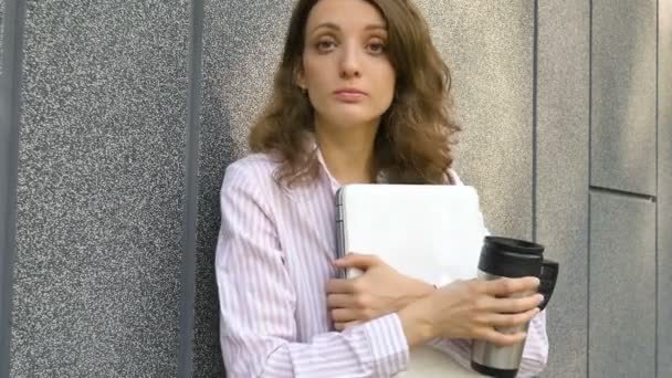 Portrait féminin de jeune femme avec ordinateur portable en argent et tasse de café en attente d'une réunion près du mur gris foncé le matin, travail à distance, pause café, concept étudiant intelligent - Séquence, vidéo