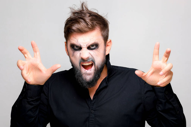 ジェスチャーを示す髭の男にハロウィンのための恐ろしいアンデッドスタイルの化粧 - 写真・画像