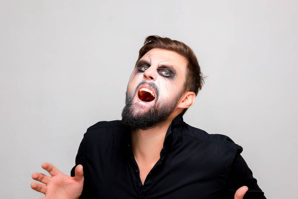 a man with a beard and makeup in the style of the undead on Halloween opened his mouth and shows his teeth - Фото, зображення